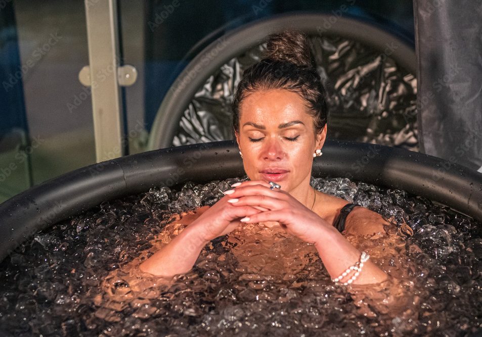 Beautiful girl ice bathing and meditating in the cold water in an inflatable pool. Wim Hof Method, cold therapy, breathing techniques, yoga and meditation